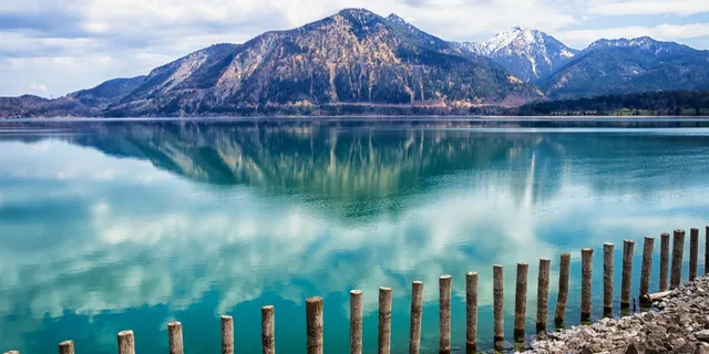 Walchensee camping: Shore of Lake Walchensee with turquoise-blue water and a mountain backdrop.