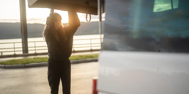 A woman is closing the camper’s trunk.