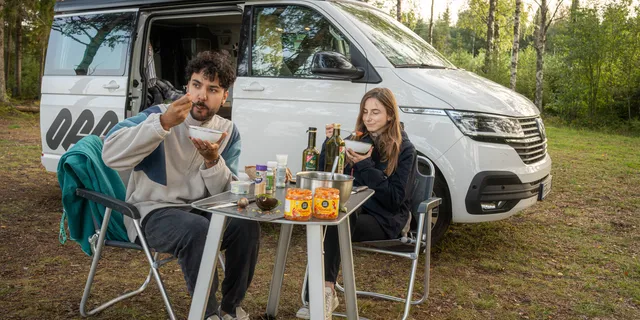 Ein Pärchen frühstückt vor einem Off Ocean Camper
