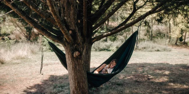 A woman is lying in a hammock surrounded by trees.