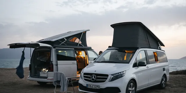 A Mercedes Marco Polo van and a VW California Ocean van are parked by the sea while wintering in Spain.