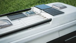RV power supply with solar system: The roof of a camper with solar panels standing on the meadow.