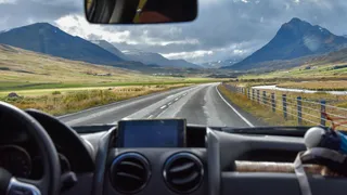 View from the window of a camper on the road and mountain landscape in the background during a tour through Iceland