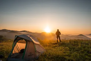 Man at sunrise before his tent at wild camp