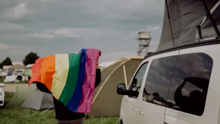 A person holding a rainbow flag is standing next to a camper – the Gay Travel Index evaluates how LGBTQ-friendly countries are worldwide.