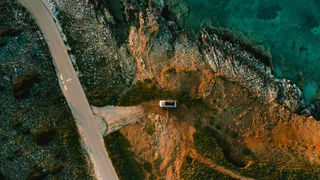 Drohnenaufnahme von Camper an Meer mit Klippen
