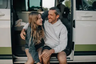 Couple sitting in the door of a camper