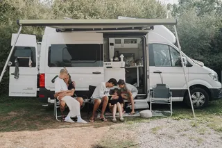 Family with children sitting in front of their camper