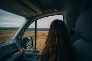 A woman looks from a car window onto the Scottish landscape.