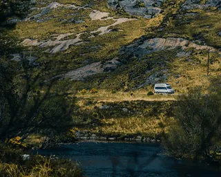 A camper runs a road through green hills in the distance.