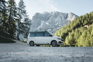 A VW camper is in front of a mountain scenery at the campsite in Albania.