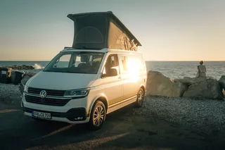 A CamperBoys Van stands on the shores of a lake.