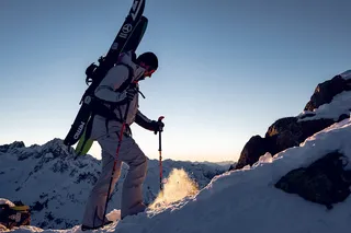 A man in and with ski equipment brides a mountain.