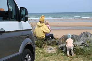 Mutter mit zwei Kindern mit Camper am Strand in Holland