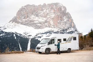 A Mooveo camper is on a road in the mountains.