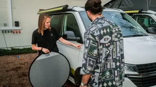 Buy Campervan: A woman shows a man a used off camper.