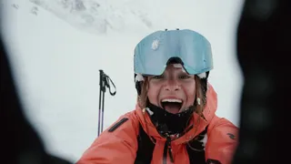 Young woman with ski equipment radiates into the camera