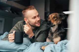 Mann und Hund liegen im Bett des Kastenwagen und schauen raus