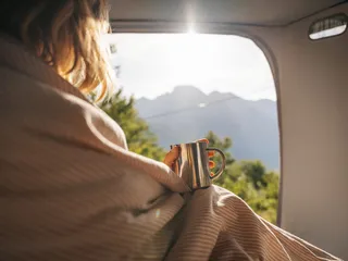 Woman sitting in the camper with a hot tub and tea and looking out the window