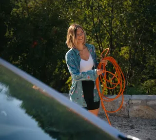 Frau beim Campen mit Wasserschlauch