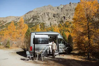 A man is standing by the camper in the mountains in Italy