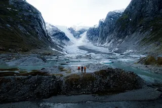 Three men are in walking equipment in a glacier in Norway.