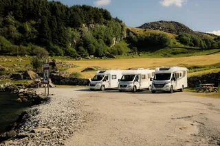 Three campers stand next to each other on a parking lot in Norway in the Green. Norway Secret Tips can be found in this article.