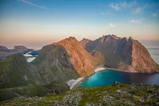 An island of the island group Vesterålen in Norway from above. You can see mountains, beach and blue sea.