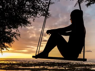 Woman swinging at sunset
