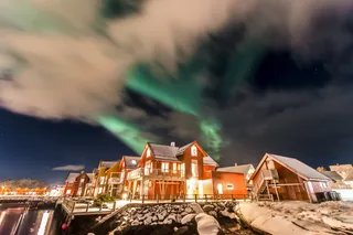 Typically red Norwegian wooden houses at night and the polar lights in the sky